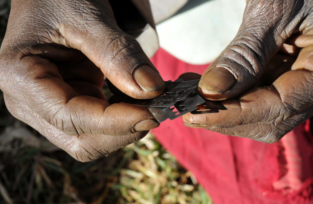 Prisca Korein, a 62-year-old traditional surgeon, holds razor blades before carrying out female genital mutilation on teenage girls from the Sebei tribe in Bukwa district, about 357 kms (214 miles) northeast of Kampala, December 15, 2008. The ceremony was to initiate the teenagers into womanhood according to Sebei traditional rites. Credit: James Akena via Reuters