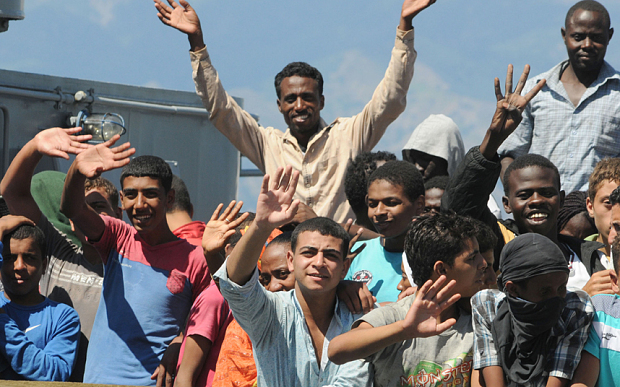 Migrants wave from the deck of the Croatian vessel SB 72 Mohorovicic prior to being disembarked at Reggio Calabria harbor, Italy. The SB 72 Mohorovicic rescued some 350 migrants and one body from a smugglers boat in the Mediterranean Sea.