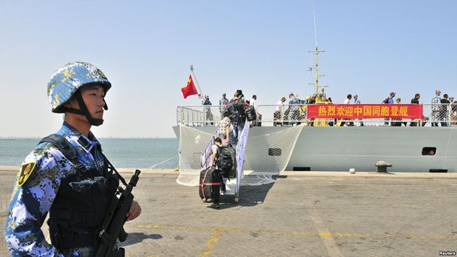 FILE - A navy soldier (L) of People's Liberation Army (PLA) stands guard as Chinese citizens board the naval ship 
