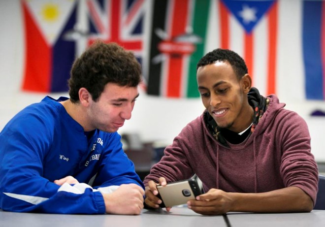 In this Monday, Dec. 14, 2015 photo, Austin Wing, left, and Abdi Shariff check out pictures on Shariff's phone at Lewiston High School in Lewiston, Maine. The two students were players on the state championship-winning soccer team. In Lewiston, white residents now see the black newcomers want the same things they do _ a safe place to raise a family, good schools, freedom and jobs, said Abdi Said, a refugee who was originally put in San Jose, California, before he moved to Lewiston. (AP Photo/Robert F. Bukaty)