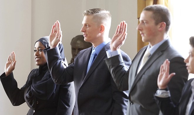 Gabe Souza/Staff Photographer Zahra Abu, left, is sworn in along with Darrel Gibson, David Moore and Concetta Puleo during Friday’s ceremony at Portland City Hall. Abu is Portland’s first Somali officer.