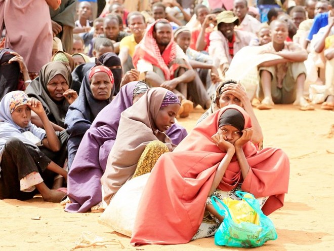 Newly arrived Somali refugees sit in a queue outside a food distribution centre at the Ifo refugee camp in Dadaab in August 2013 /FILE