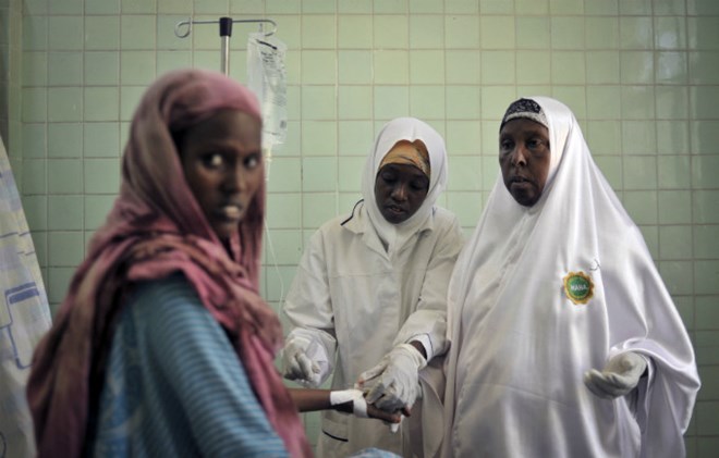 Two midwives place an intravenous drip for a patient at the maternity ward of Banadir Hospital in Mogadishu. © UN Photo/Tobin Jones