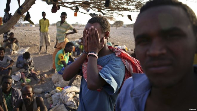 FILE - An illegal immigrant from Ethiopia covers his face as he waits with others for a boat to cross into Yemen outside the town of Obock, north Djibouti.