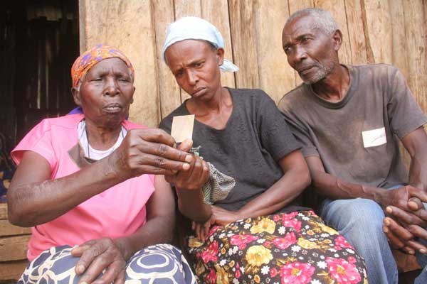 Ms Sarah Wangechi (centre) and her relatives view the photo of her husband, Amos Njogu, at their home in Nyaribo, Nyeri County on October 25. Amos Njogu was among 12 people killed in an attack by Al -Shabaab militants. PHOTO | NICHOLAS KOMU | NATION MEDIA GROUP