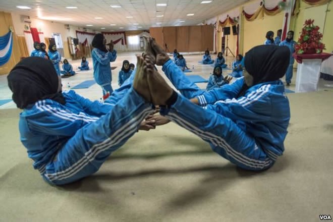 Two women practice a pose during a mind-body wellness program for survivors of trauma in Mogadishu, Somalia, Jan. 16, 2017. (J. Patinkin/VOA)