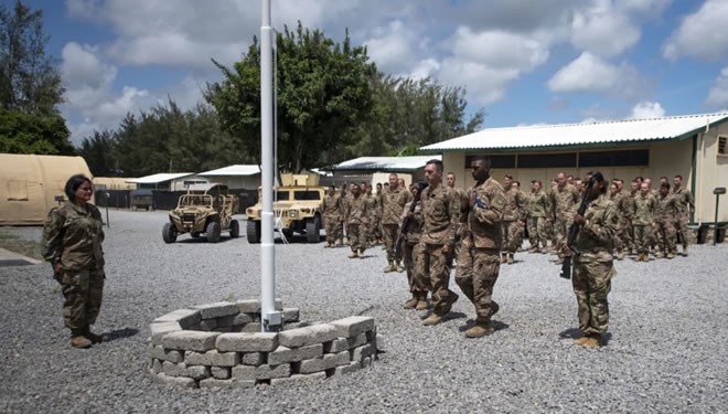Service members from the 475th Expeditionary Air Base Squadron conduct a flag-raising ceremony, signifying the change from tactical to enduring operations, at Camp Simba, Manda Bay, Kenya, on Aug. 26. (Staff Sgt. Lexie West/U.S. Air Forc
