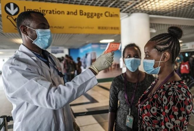 A worker of the Ethiopian Public Health Institute (EPHI) measures an airport staff member's temperature at a control point at the Bole International Airport, in Addis Ababa, on March 17, 2020.   | Photo Credit: AFP