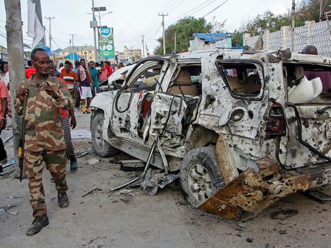 A member of the security forces walks past a wrecked vehicle outside the Elite Hotel in Mogadishu, Somalia Monday, Aug. 17, 2020. Image Credit: AP
