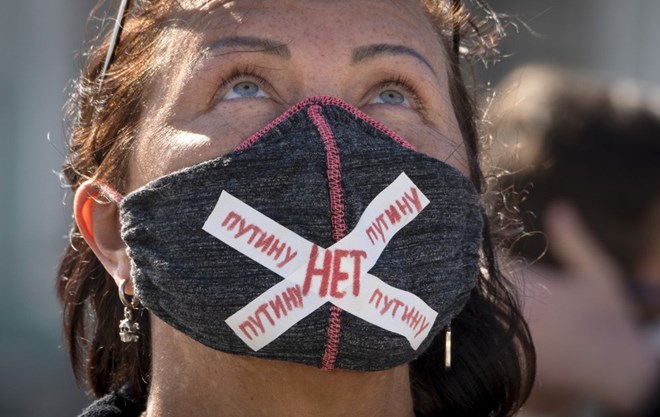 A woman wears a face mask to protect against coronavirus infection with a sign "No to Putin" during a protest against constitutional amendments at the Palace Square in St.Petersburg, Russia, Wednesday, July 1, 2020. The vote on the constitutional amendments that would reset the clock on Russian President Vladimir Putin's tenure and enable him to serve two more six-year terms is set to wrap up Wednesday. (AP Photo/Dmitri Lovetsky)