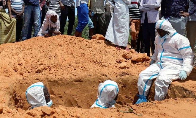Somali workers in protective suits stand inside a grave in Mogadishu. Photograph: Feisal Omar/Reuters