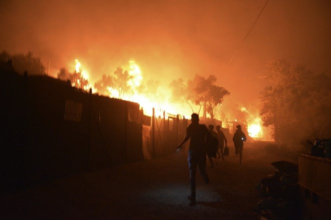 Refugees and migrants run as fire burns in the Moria refugee camp on the northeastern Aegean island of Lesbos, Greece, on Wednesday, Sept. 9, 2020. Fire Service officials say a large refugee camp on the Greek island of Lesbos has been partially evacuated despite a COVID-19 lockdown after fires broke out at multiple points around the site early Wednesday. (AP Photo/Panagiotis Balaskas)