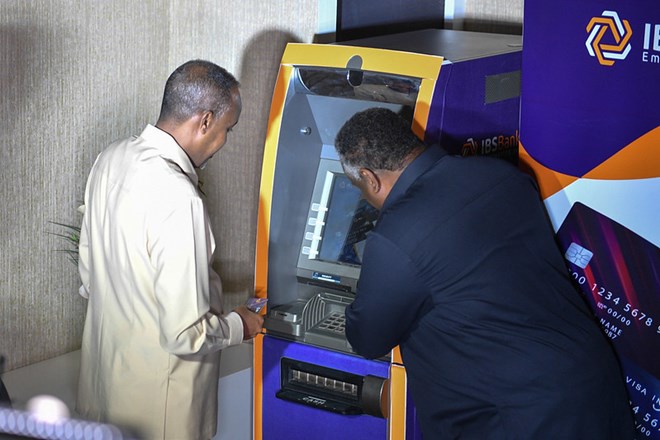The Prime Minister of the Federal Republic of Somalia, Mohamed Hussein Roble, withdraws money using a VISA card at an ATM during the launch of the VISA card service by the International Bank of Somalia (IBS) in Mogadishu, Somalia on 7 July 2021. The American digital financial payments service Visa, has partnered with IBS Bank to introduce Somalia’s first Visa financial card payment service. AMISOM photo / Fardowsa Hussein