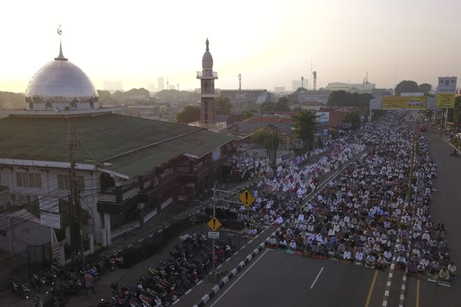 In this photo taken using a drone, Muslims attend for Eid al-Fitr prayer marking the end of the holy fasting month of Ramadan on a street in Bekasi, West Java, Indonesia, Monday, May 2, 2022. (AP Photo/Achmad Ibrahim)