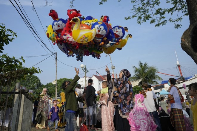 A woman buys a balloon after Eid al-Fitr prayers to mark the end of the holy fasting month of Ramadan at Sunda Kelapa port in Jakarta, Indonesia, Monday, May 2, 2022. (AP Photo/Tatan Syuflana)