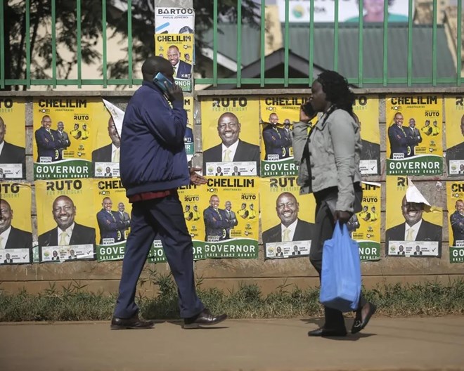 People walk in front of election posters in Eldoret, Kenya, Wednesday Aug. 10, 2022. Kenyans are waiting for results in the presidential elections that saw opposition leader Raila Odinga face Deputy President William Rutoto in their bid to succeed President Uhuru Kenyatta who stayed in power for a decade. BRIAN INGANGA / AP PHOTO