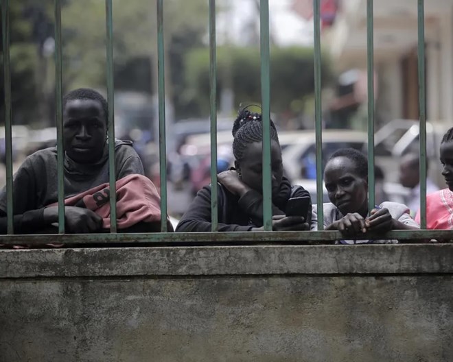 People stand outside a polling station in Eldoret, Kenya, Wednesday Aug. 10, 2022. Kenyans are waiting for results in the presidential elections that saw opposition leader Raila Odinga facing Deputy President William Rutoto in their bid to succeed President Uhuru Kenyatta who stayed in power for a decade. BRIAN INGANGA / AP PHOTO