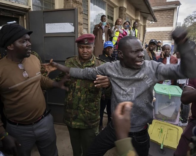 People argue with others from different parties and security forces trying to keep order, after a few ballot boxes were discovered with their seals broken, at a tallying center in the Mathare area of Nairobi, Kenya Wednesday, Aug. 10, 2022. Kenyans are waiting for the results of a close presidential election in which the turnout was lower than usual. BEN CURTIS / AP PHOTO