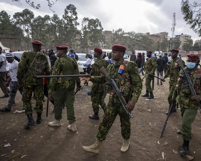 A police officer gestures indicating people to get back as police try to push back an angry crowd, after a few ballot boxes were discovered with their seals broken, at a tallying center in the Mathare area of Nairobi, Kenya Wednesday, Aug. 10, 2022. Kenyans are waiting for the results of a close presidential election in which the turnout was lower than usual. BEN CURTIS / AP PHOTO