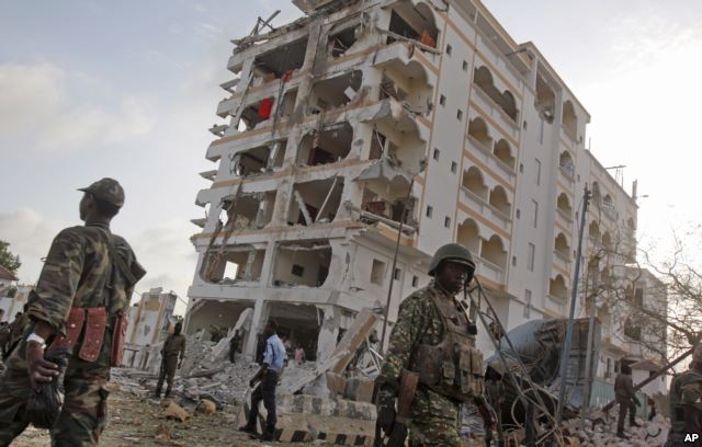An African Union (AU) soldier walks past the scene of destruction following a suicide car bomb attack in the capital Mogadishu, Somalia, July 26, 2015.