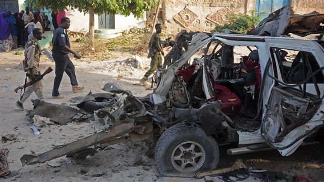 Somali soldiers and local residents look at a wrecked car at the site of a car bomb blast at Yaqshid district in Mogadishu on April 18, 2016. (AFP photo)