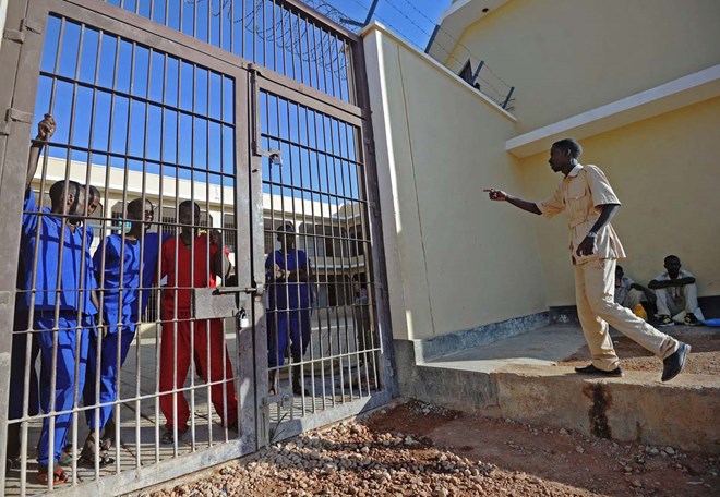 A prison warden talks to prisoners who stand behind a gate of a prison in Garowe, Puntland state, in northeastern Somalia, on December 14, 2016. The prison facilitates the rehabilitation of convicted Somali pirates and suspected Al-Shabaab jihadists. (MOHAMED ABDIWAHAB/AFP/Getty Images)