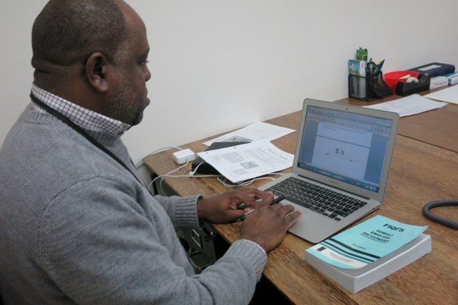 Portland's new Somali teacher, Salaad O'Barrow, works on language curriculum with a  dictionary for one of two Somali languages on his desk. O'Barrow is designing lessons for both languages: Maxaa and Maay-Maay. Rob Manning/OPB