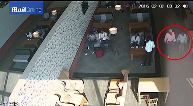 Newly-released footage shows two men handing a laptop to a passenger after he passed through security. One of the two men is wearing a security jacket.