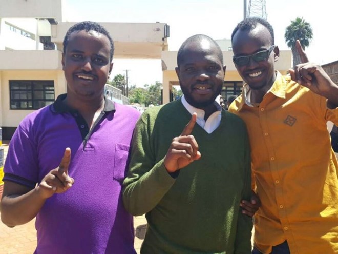 ONE-FINGER SALUTE: Yassin Juma (centre) with friends at the Muthaiga police station yesterday. He allegedly shared “sensitive” information on the Shabaab attack in Somalia
