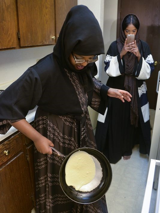 Faisa Omar, 17, uses gravity to spread the batter for the malawah, or crepes, that she makes for the breaking of her family's Ramadan fast as her twin sister, Fosia, plays with her cellphone on Tuesday, June 7. The family gathers in their mother's Waite Park apartment each night of Ramadan.
(Photo: Kimm Anderson, kanderson@stcloudtimes.com)