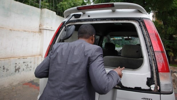 Abdiqadir Dulyar, director for the Somali television station Horn Cable, looks at the smashed window of a car that was carrying journalists working for his station, that unidentified gunmen opened fire on last week although no one was hurt, in Mogadishu, Somalia Tuesday, May 3, 2016. (AP / Farah Abdi Warsameh)