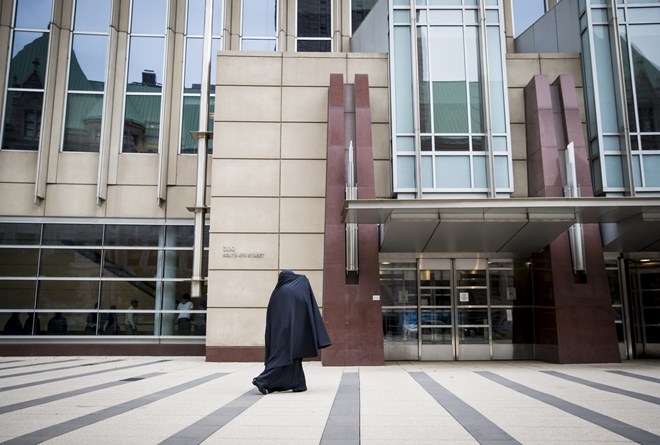 A woman covered her face from the media as she arrived at the Federal Courthouse in Minneapolis before the sentencing for three of the nine ISIL recruit defendants on Monday.
