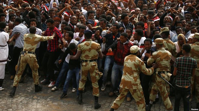 FILE - Demonstrators chant slogans while flashing the Oromo protest gesture during Irreecha, the thanksgiving festival of the Oromo people, in Bishoftu town, Oromia region, Ethiopia, Oct. 2, 2016.