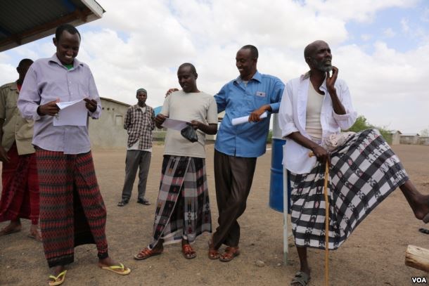 Somali Ahmed Omar Bihi and fellow refugees in Kakuma refugee camp check to see what names appear on a list for an interview with the International Organization for Migration (IOM) for potential U.S. resettlement in Kakuma, Kenya, Feb. 6, 2017. (J. Craig / VOA)