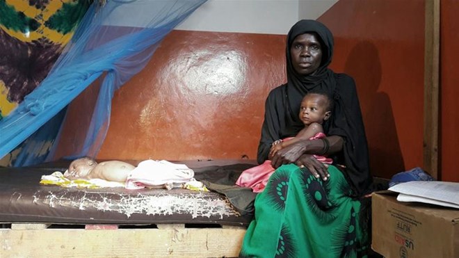 A mother with twins at a malnutrition treatment centre in Mogadishu. The baby on the bed needs days of treatment to recover from acute malnutrition. [Fahmida Miller/Al Jazeera]