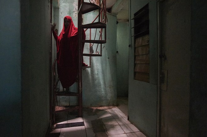 Somalian refugee Igra descends the stairs of a Jakarta boarding house. The former hotel owner fled her country in 2015 after militants threatened to cut off her hands for refusing to close down her business.