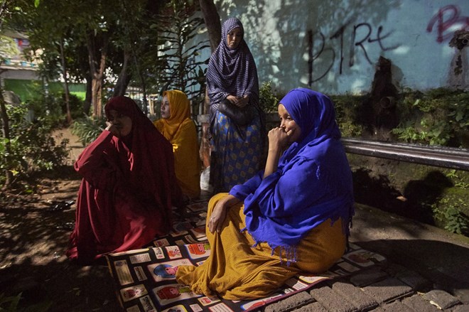 Somalia refugees sit in the street at night in Jakarta. The women say not only do they have difficulties accessing food, they also face nightly dangers from men looking for sex.