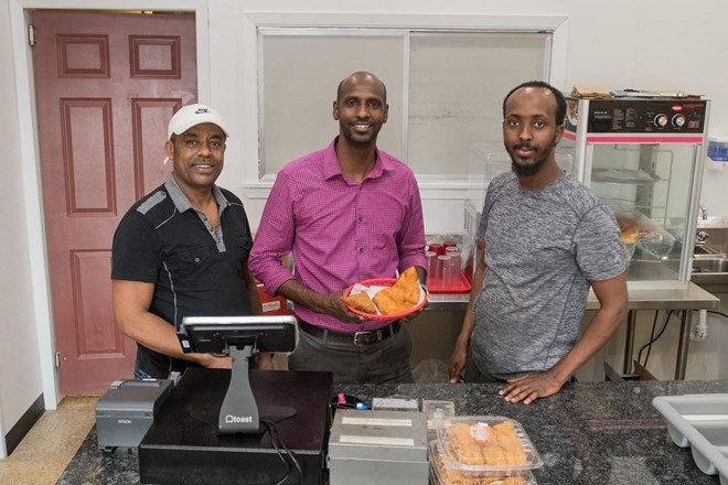 From left, Abdella Namo, Mohamed Ahmed and Ahmed Musse behind the counter at Brothers Restaurant and Grocery. Ahmed holds a basket of sambusa, an African pastry filled with ground meat or vegetables. Photo by Jackson Forderer