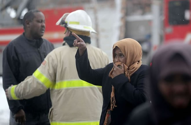 Residents of a south Minneapolis high rise were evacuated early Wednesday after a fire broke out on the 14th floor of the building, killing five people. Here, a woman who would not give her name but said she didn't live in the building points up to where the fire swept through during the early morning Wednesday, Nov. 27, 2019, in Minneapolis, MN.